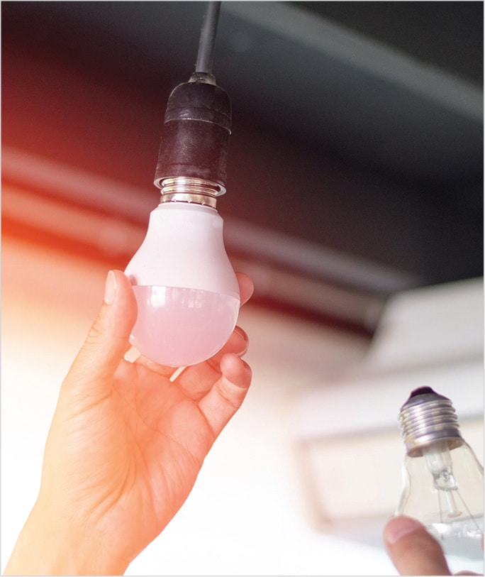 A male hand changing the LED light bulb with the other 