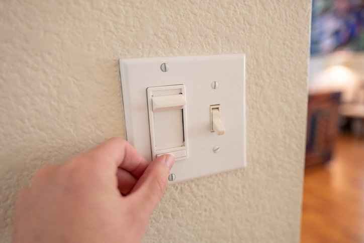 person touching a dimmer switch 