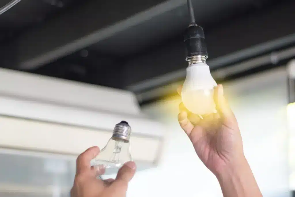 a person replacing the normal light bulb with led light bulb